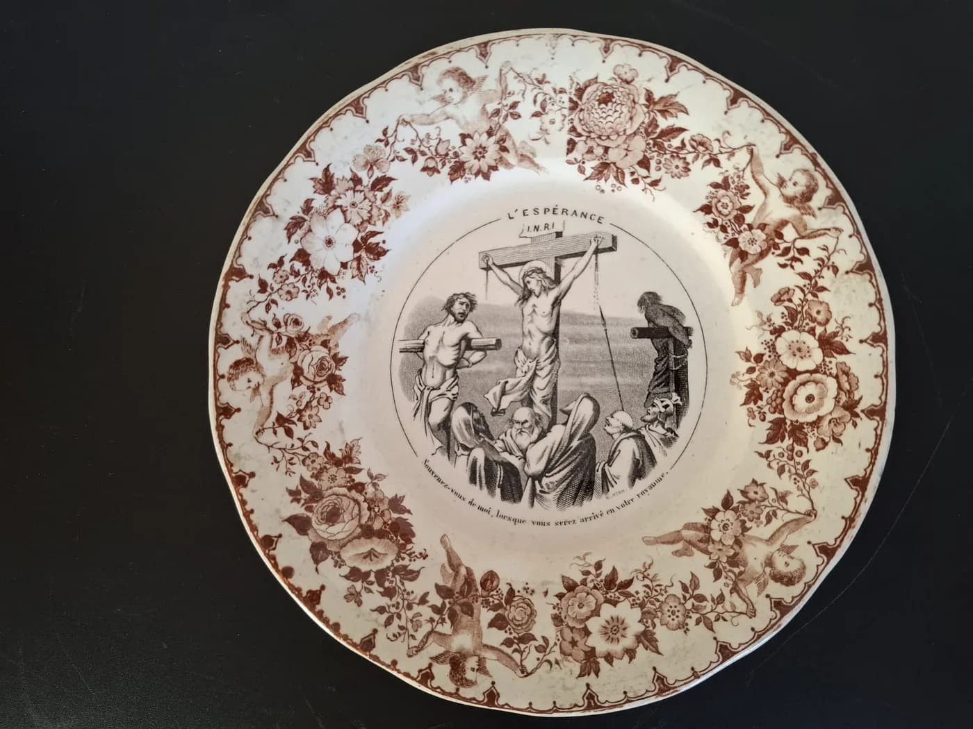 Assiette à décor imprimé brun intitulée « L'Espérance » : une scène de crucifixion entourée d'une bordure de fleurs et d'angelots.